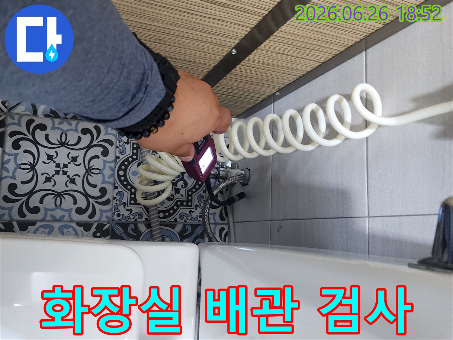 누수 엔지니어가 화장실 변기 옆 배관에서 누수 여부를 확인하기 위해 장비를 사용하고 있습니다.