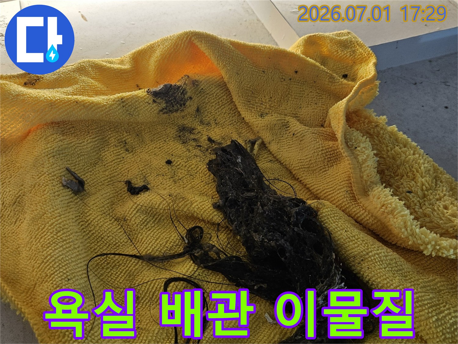 노란색 수건 위에 놓인-욕실 배수관에서 제거된-머리카락과 비누 찌꺼기 덩어리입니다-이는 배수 막힘의 주된 원인입니다
