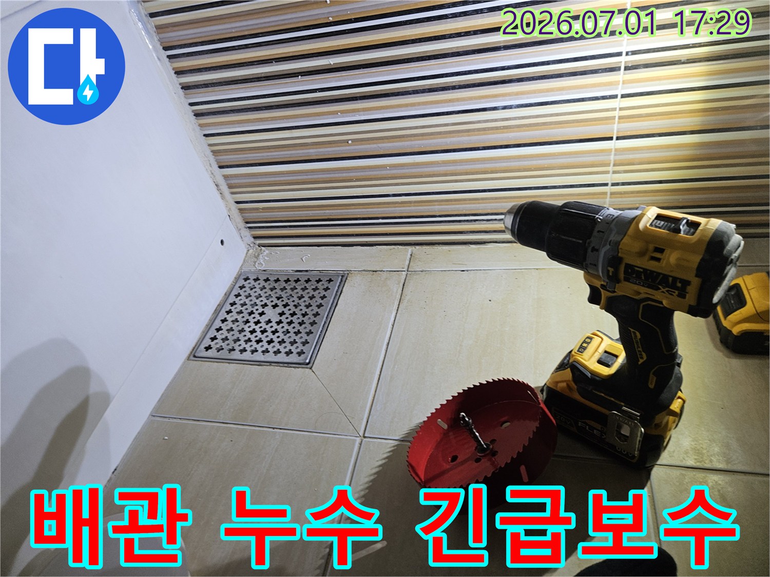 상가 화장실 배수구 주변에서-긴급 배관 누수 보수를 위해-드릴과 홀쏘를 사용하여-타일 절단 작업을 준비하는 현장입니다