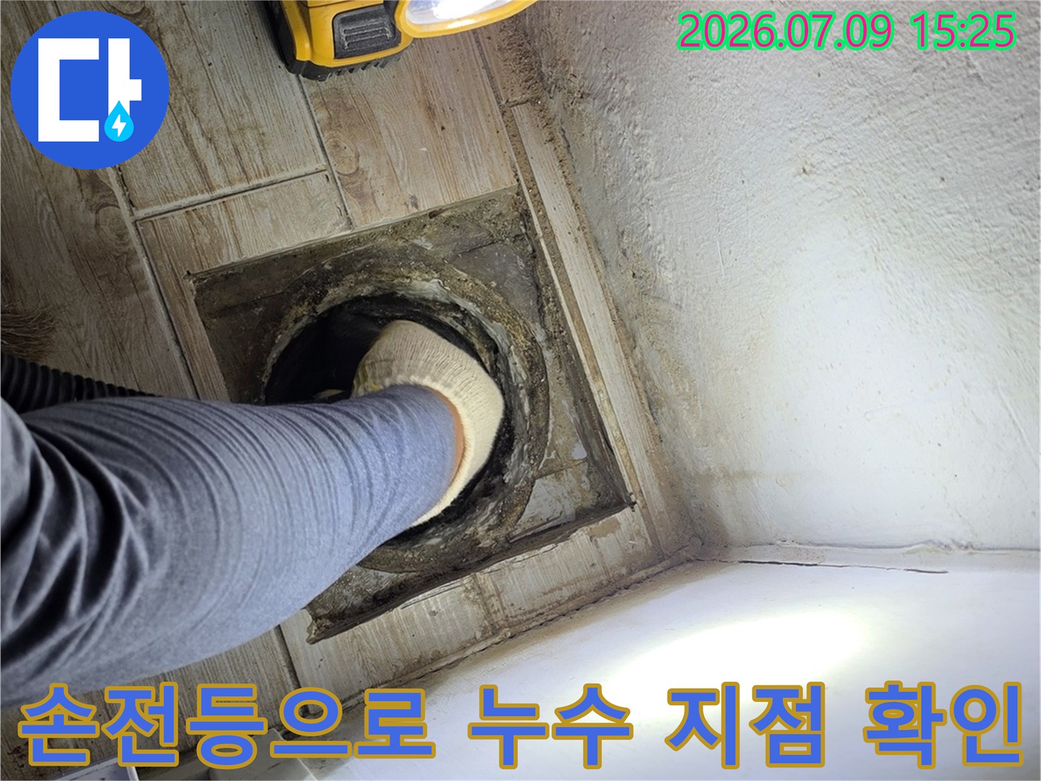 강력한 조명을 활용하여 습기가 찬 배수구 주변을 정밀하게 조사하는 모습