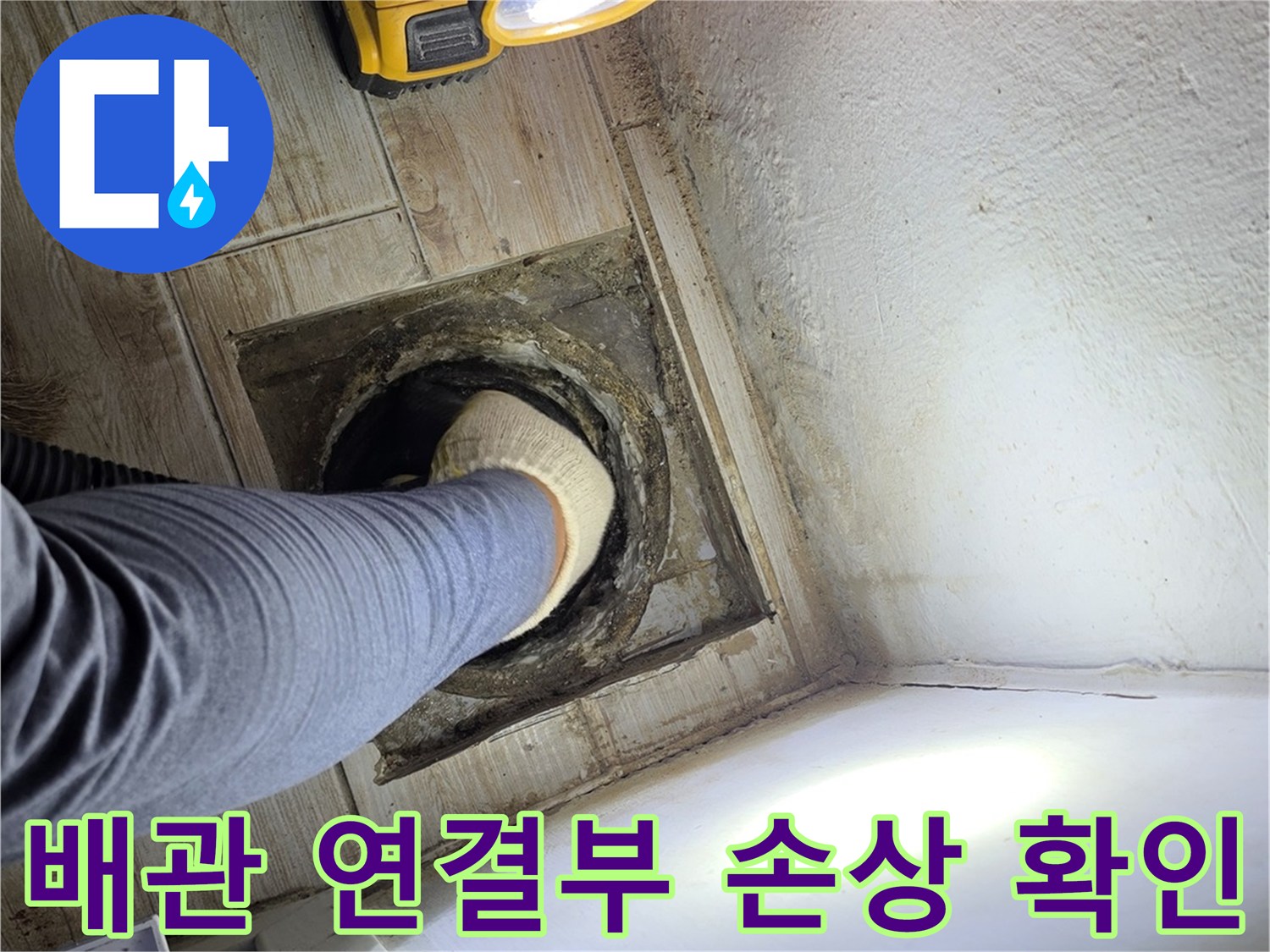손전등을 사용하여 굴착된 세탁실 배수구 주변의 파손 부위를 정밀하게 살피는 모습