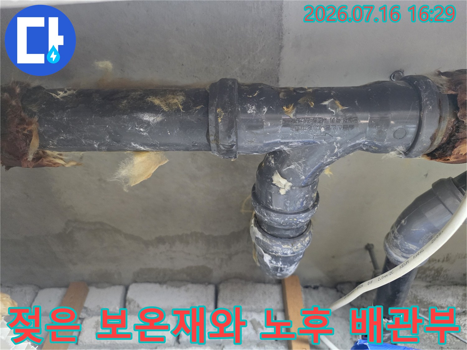 습기로 인해 변색된 보온재와 굴곡진 배수 배관 연결 부위의 누수 흔적 촬영