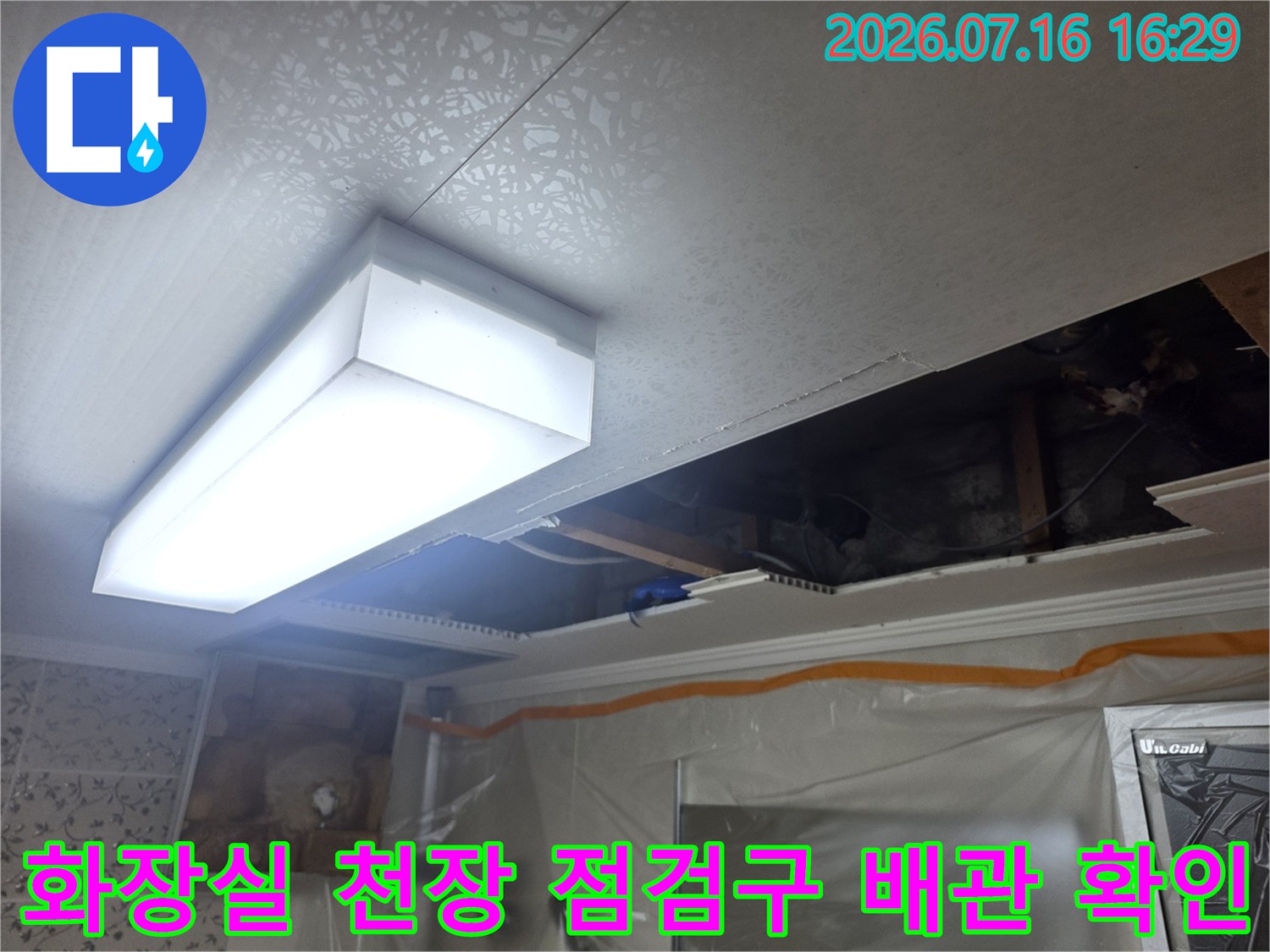 화장실 천장 점검구를 통해 노출된 배관 부위를 조사하는 모습
