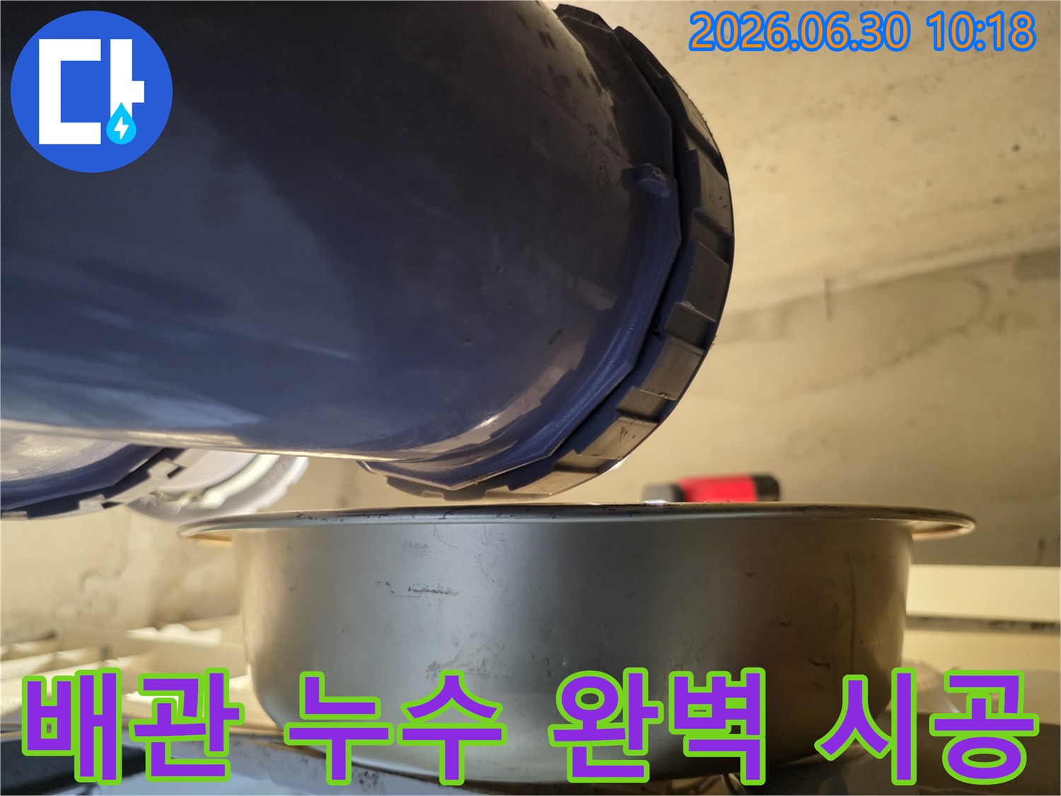 누수-현장에서-배관의-연결-부위에서-물이-새는-것을-발견하고-아래에-물받이를-놓아-누수-상황을-진단하고-완벽한-시공을-위한-계획을-세우는-모습입니다.