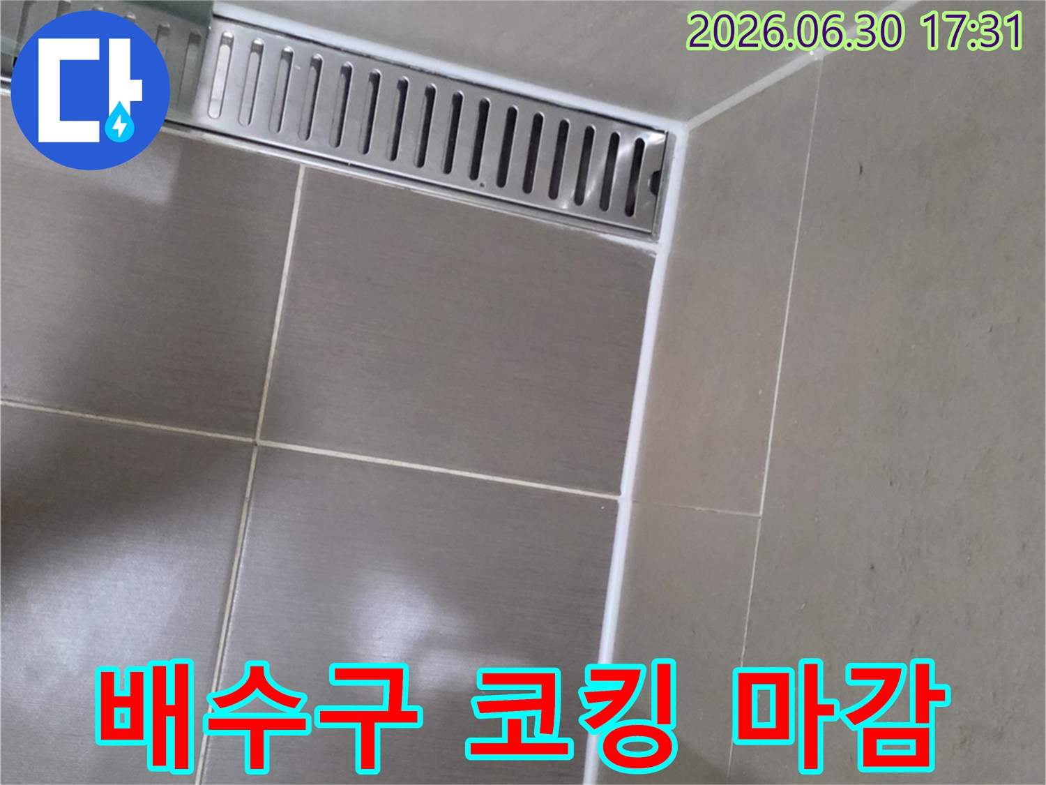 욕실 바닥의-선형 배수구와-주변 타일-경계면에-새롭게 적용된-하얀색-실리콘 코킹 마감 상태를-선명하게-보여줍니다.