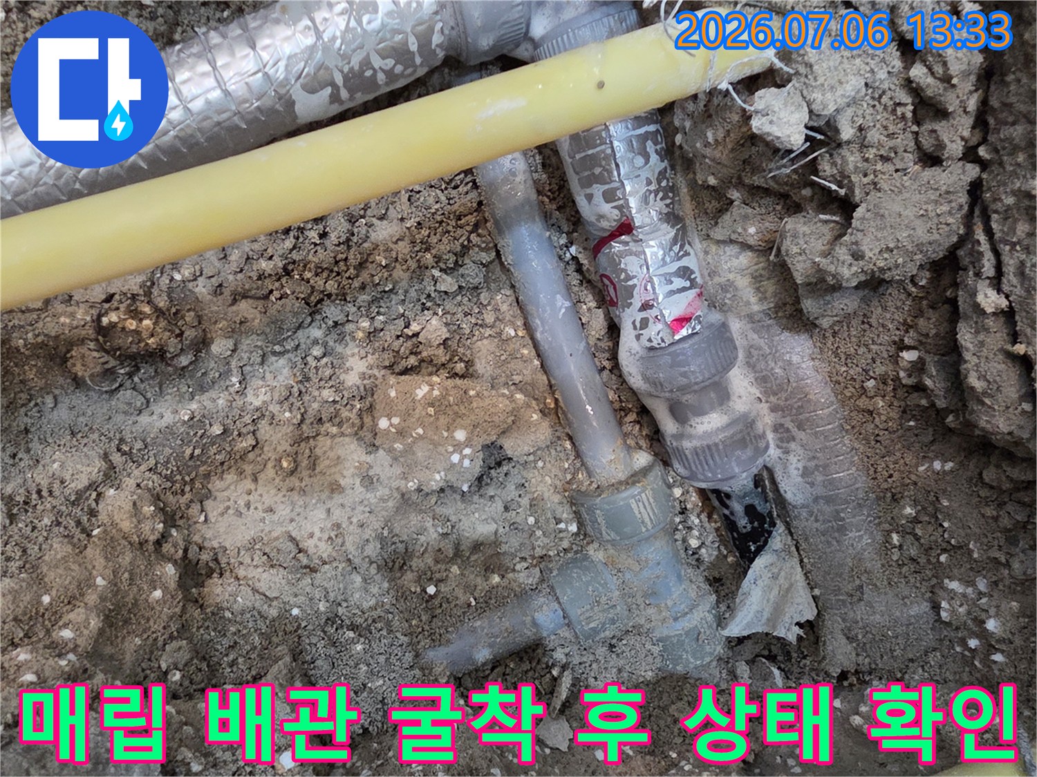 노란색과 흰색 보온재로 감싸진 복합적인 배관 구조의 굴착 현장
