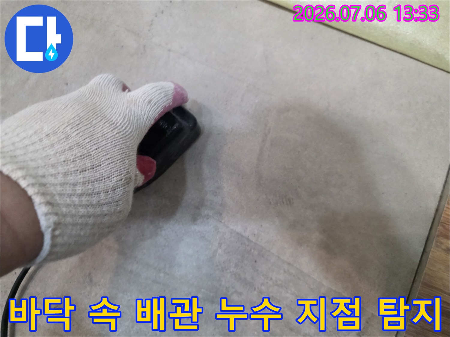청음기 장비를 손으로 잡고 바닥을 훑으며 누수 위치를 정밀하게 파악하는 모습