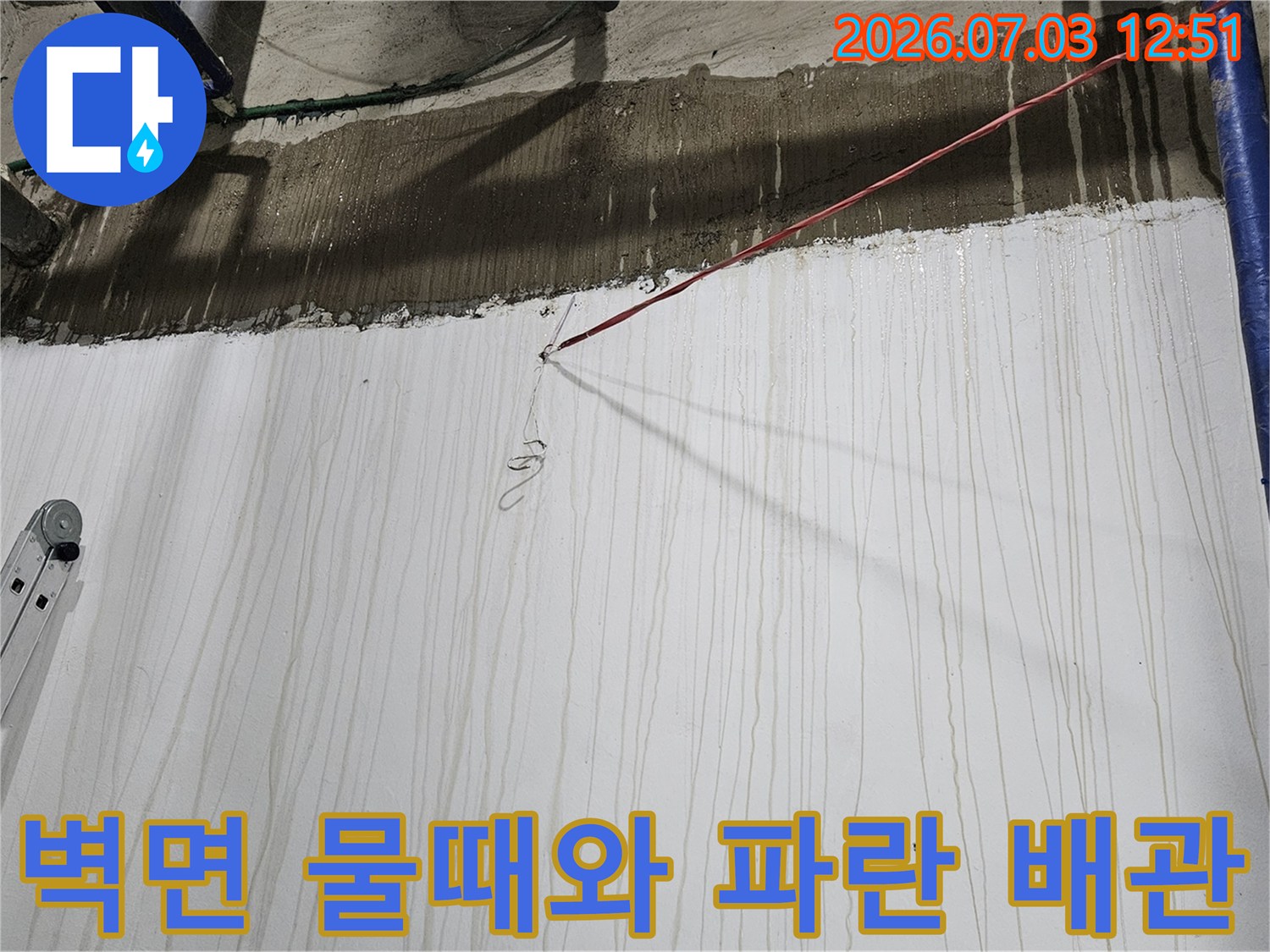 파란색 배관이 설치된 지하 벽면에 수직으로 형성된 누수 오염 자국들