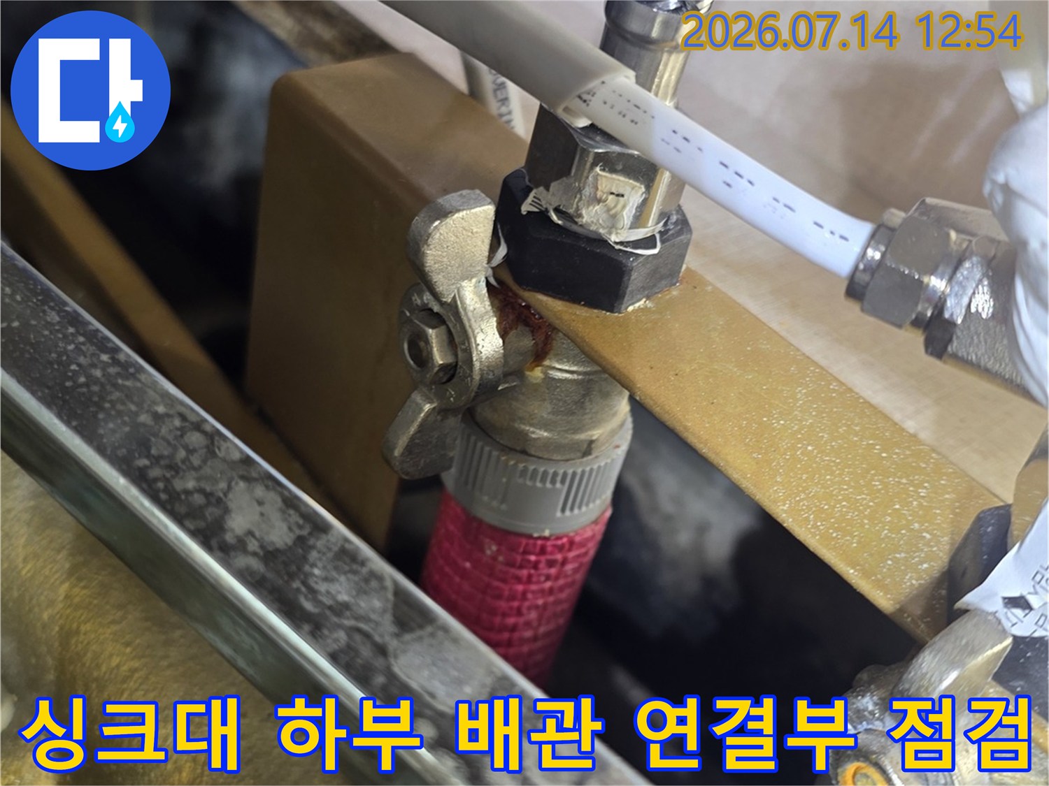싱크대 아래 노출된 급수 및 온수 배관의 연결 부위와 밸브 체결 상태를 확인하는 모습