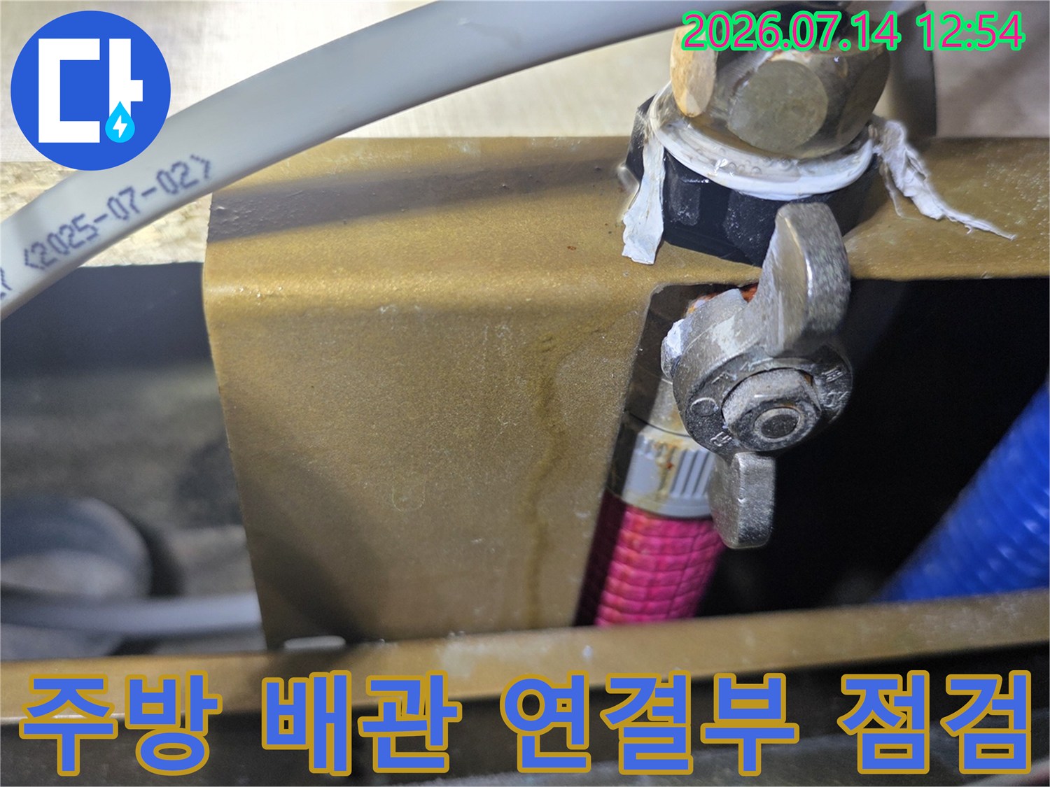 싱크대 하부의 노출된 배관과 밸브 부속을 정밀하게 점검하는 모습