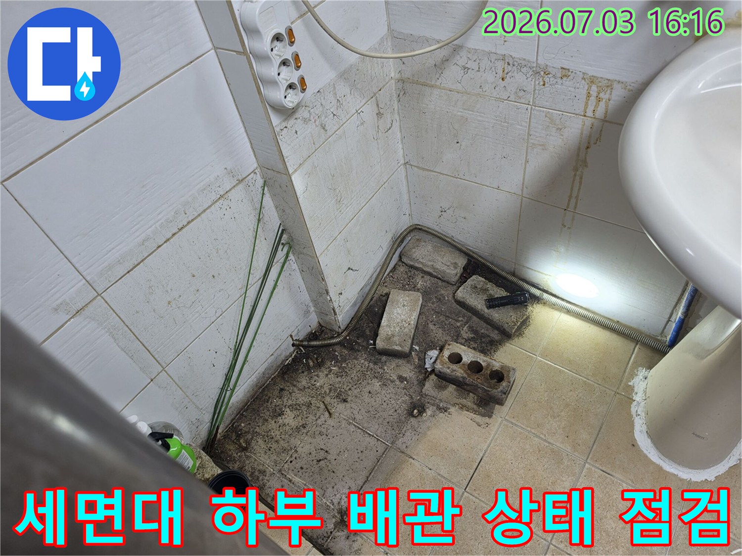 배관 연결부의 오염과 벽 타일 변색을 통해 누수 경로를 파악하는 현장 사진