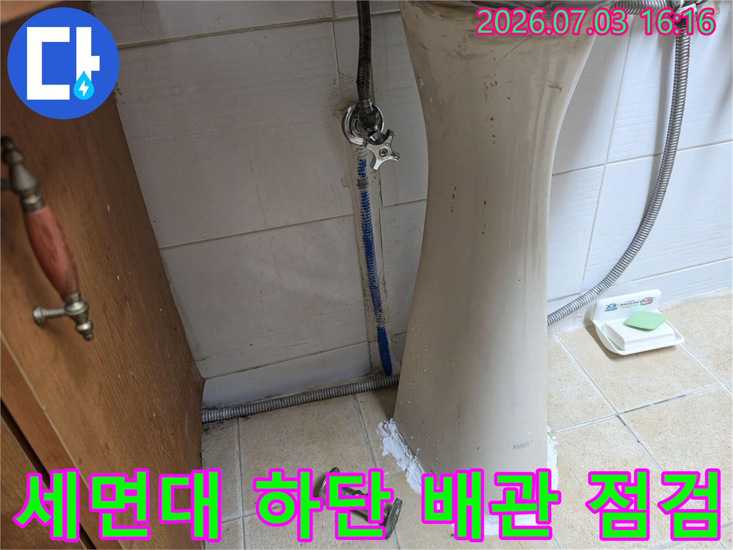세면대 아래쪽 노출된 배관과 연결 부위를 정밀하게 점검하는 모습