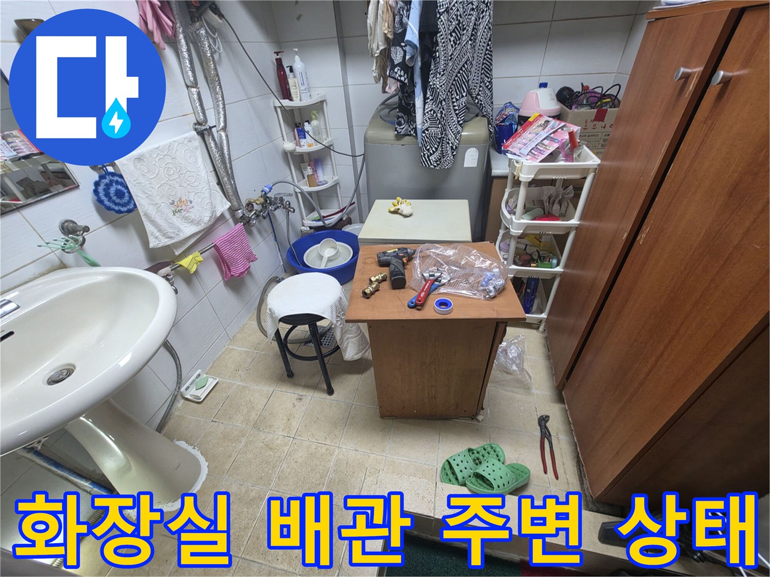 세면대 하단 공간-누수 흔적이 남은 배관과 작업 도구들
