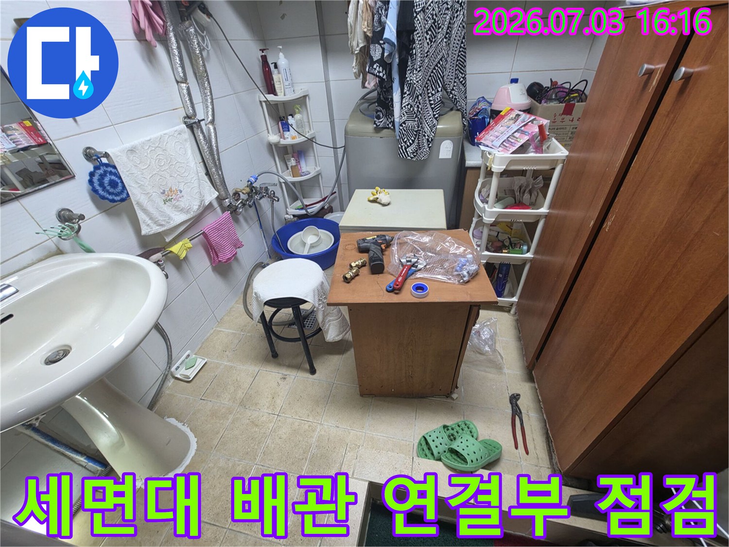 세면대 하단부의 굴곡진 배관과 작업 도구들이 배치된 모습