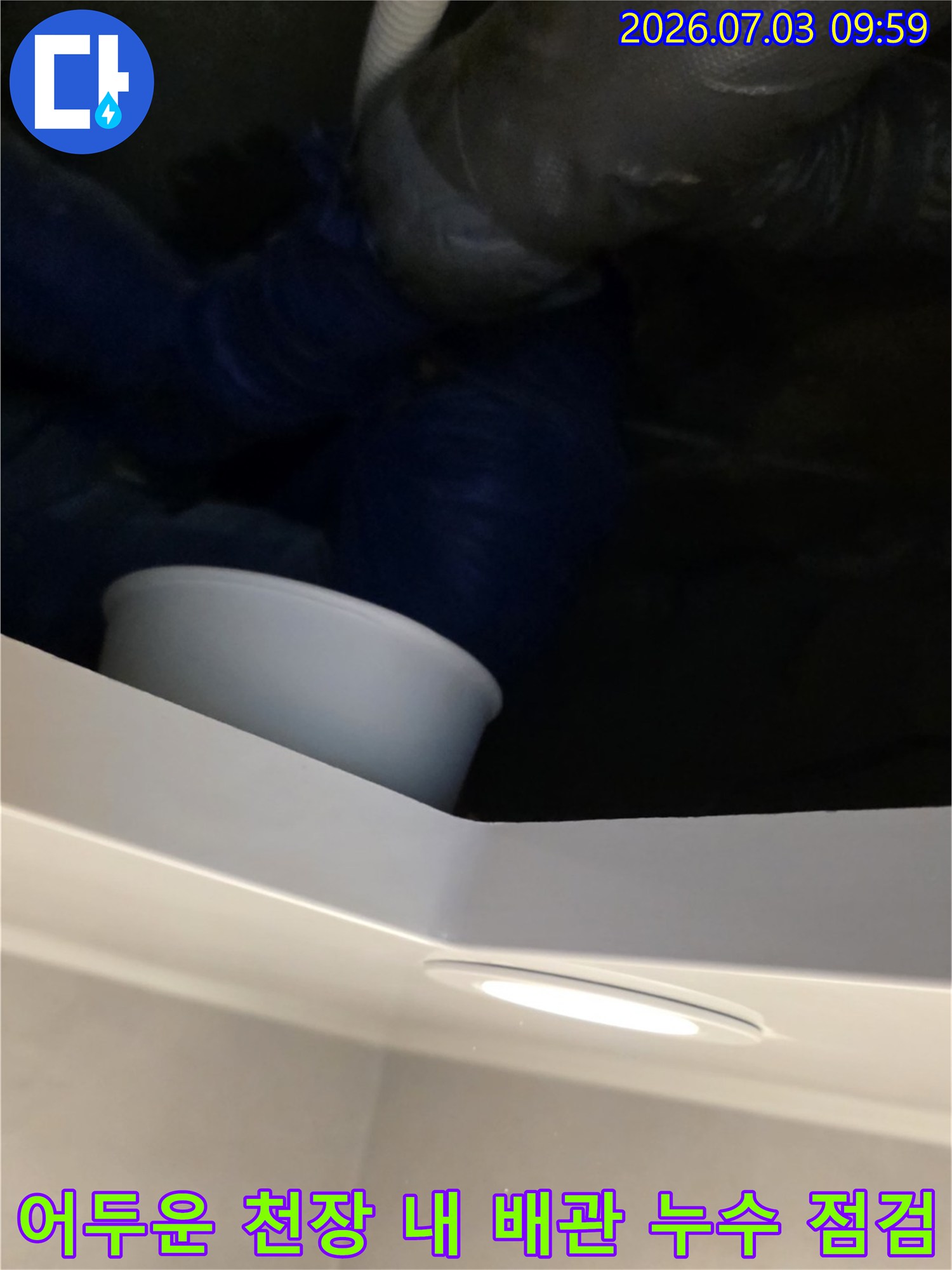 천장 안쪽의 어두운 공간에서 배관 연결부의 노후 상태를 체크하는 과정