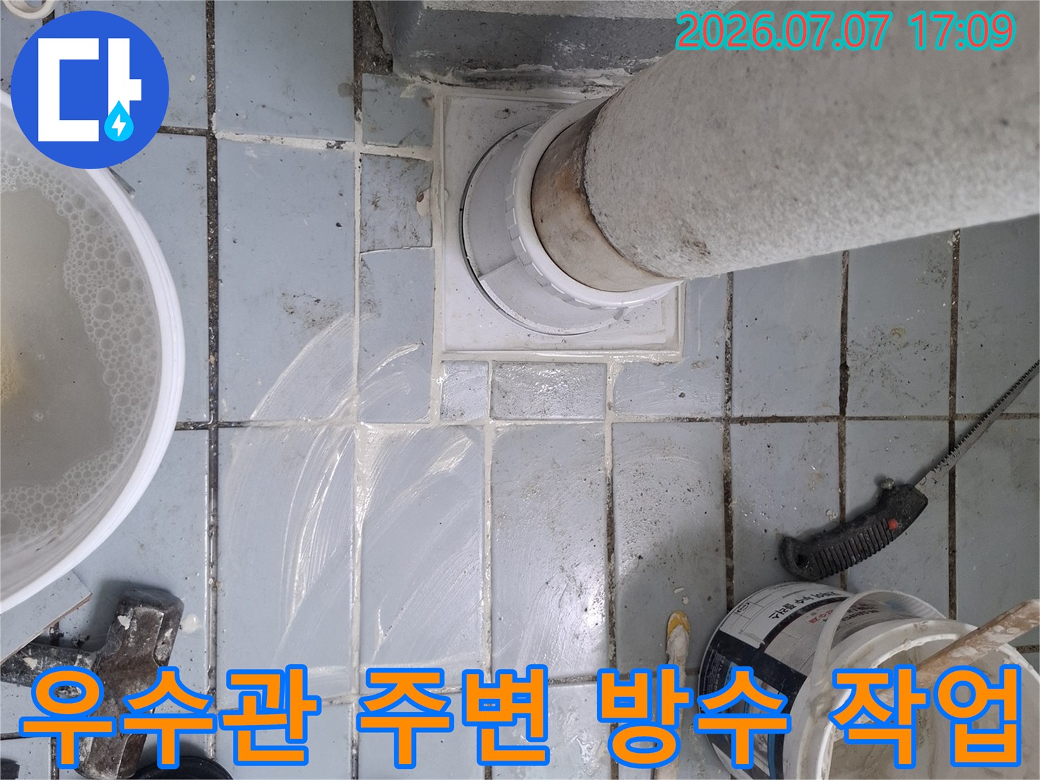 우수관 주변에 덧방된 흰색 배관과 누수 보수를 위한 도구들이 배치된 현장