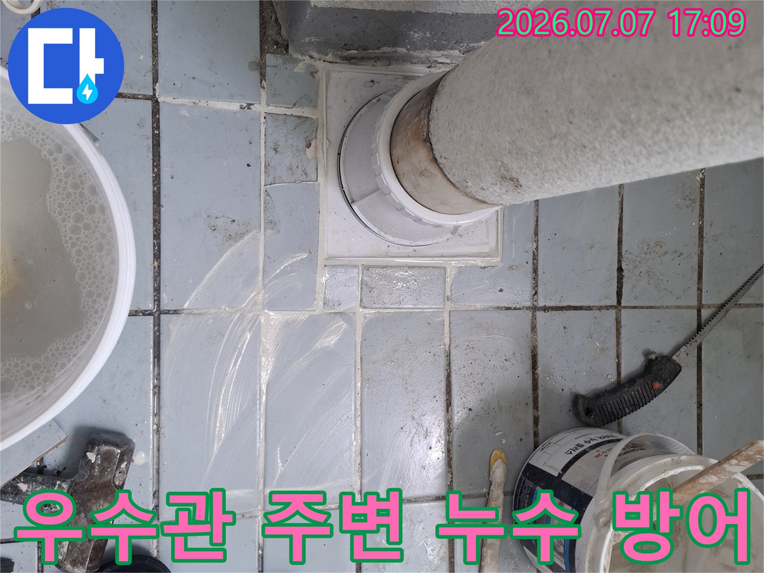 전문가용 도구와 재료를 갖추고 우수관 배관 부위를 정밀하게 점검하는 모습
