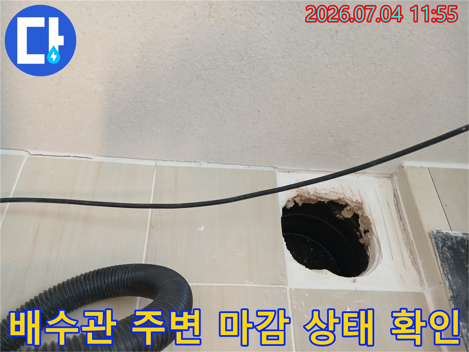 노출된 배수 트랩과 파손된 타일 주변의 누수 징후 사진