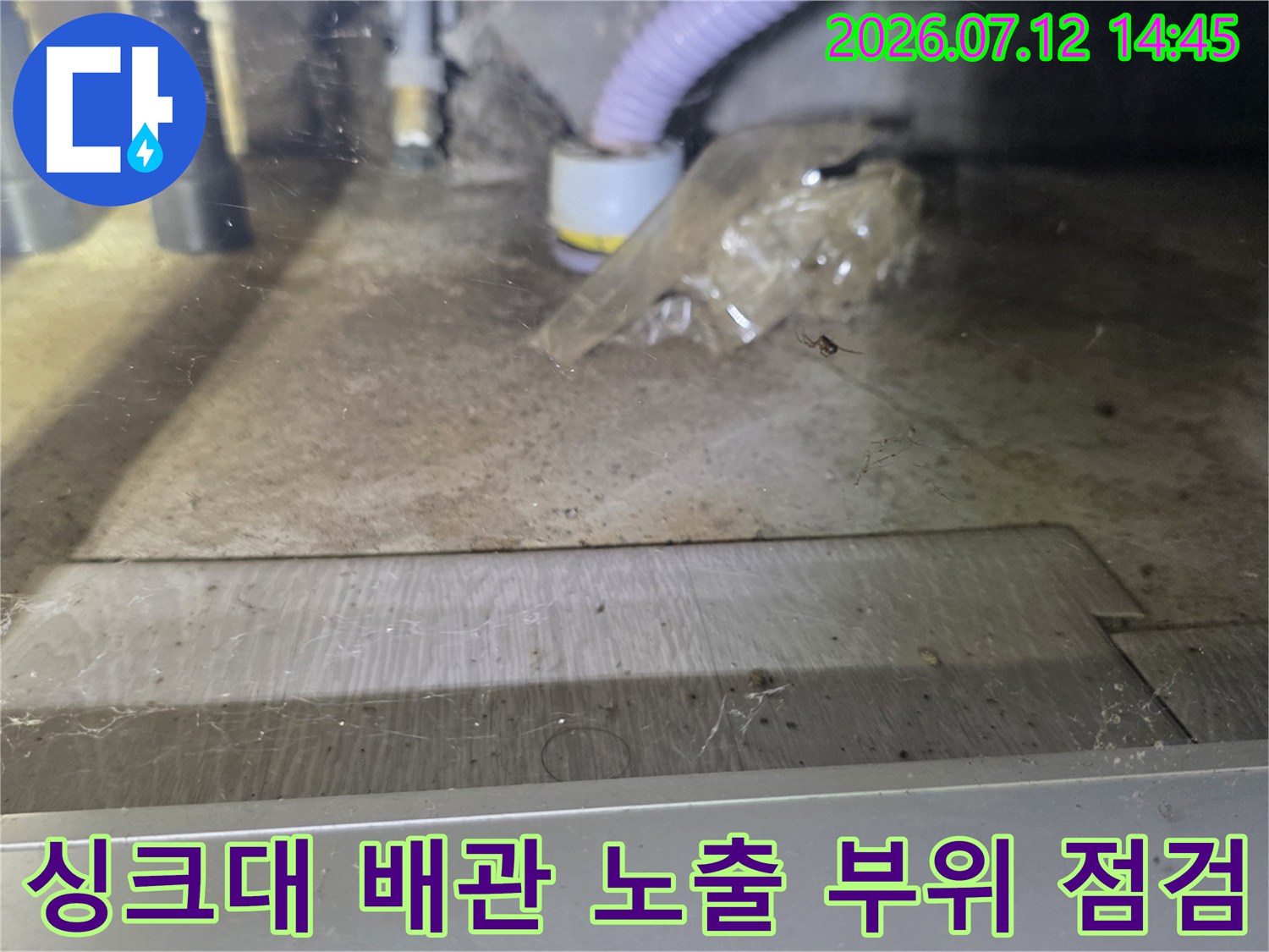 싱크대 밑에 위치한 하수 배관의 연결 상태와 바닥면을 촬영한 사진