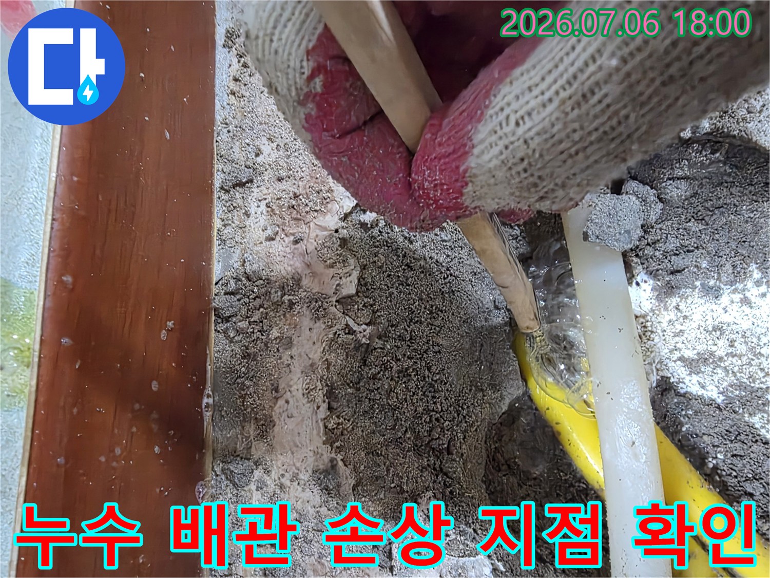 작업복을 입은 전문가가 파손된 노란색 배관 위치를 정확히 짚어내는 모습