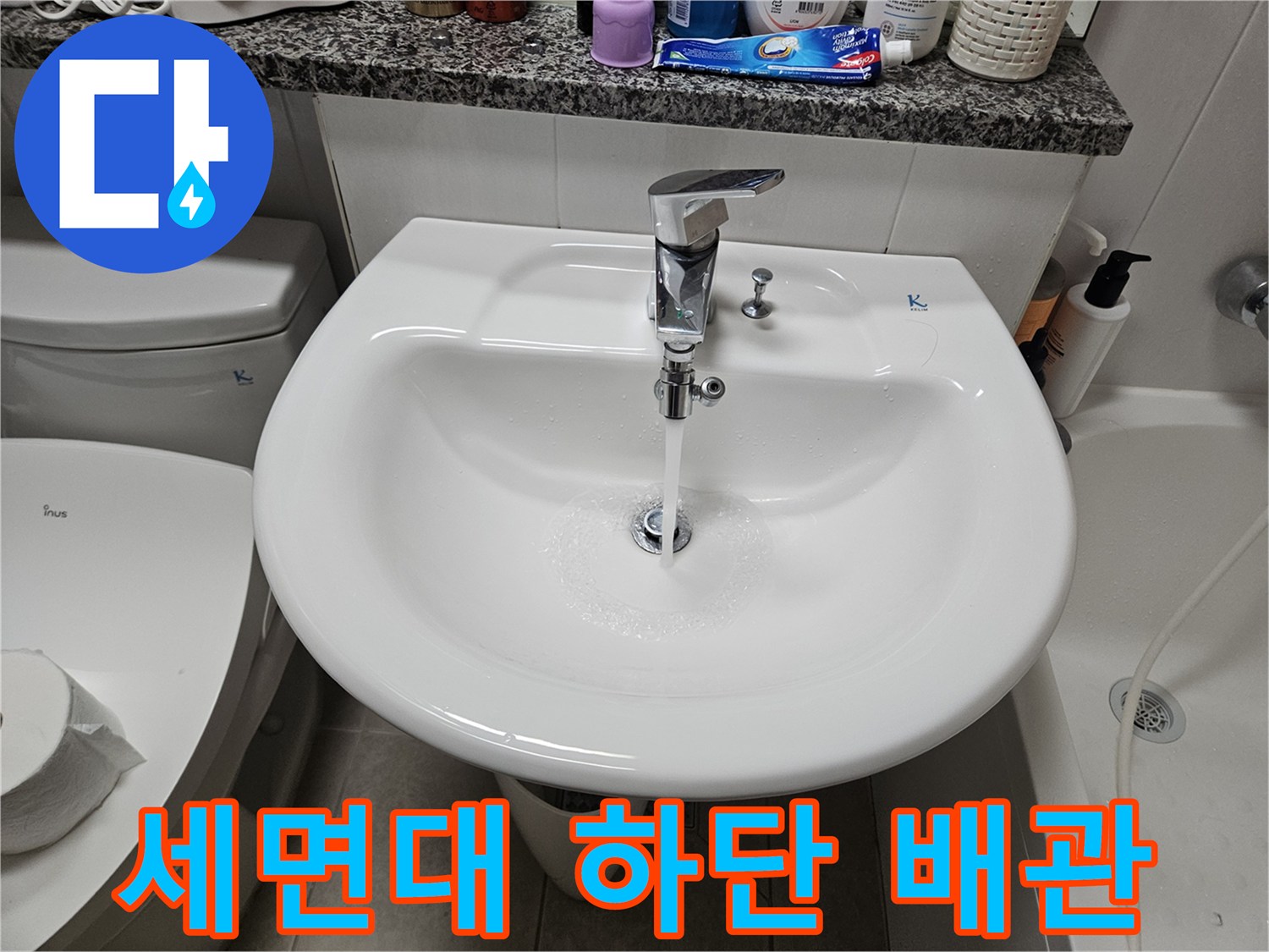 세면대 아래로 뻗어 나온 은색 수전 배관 사진