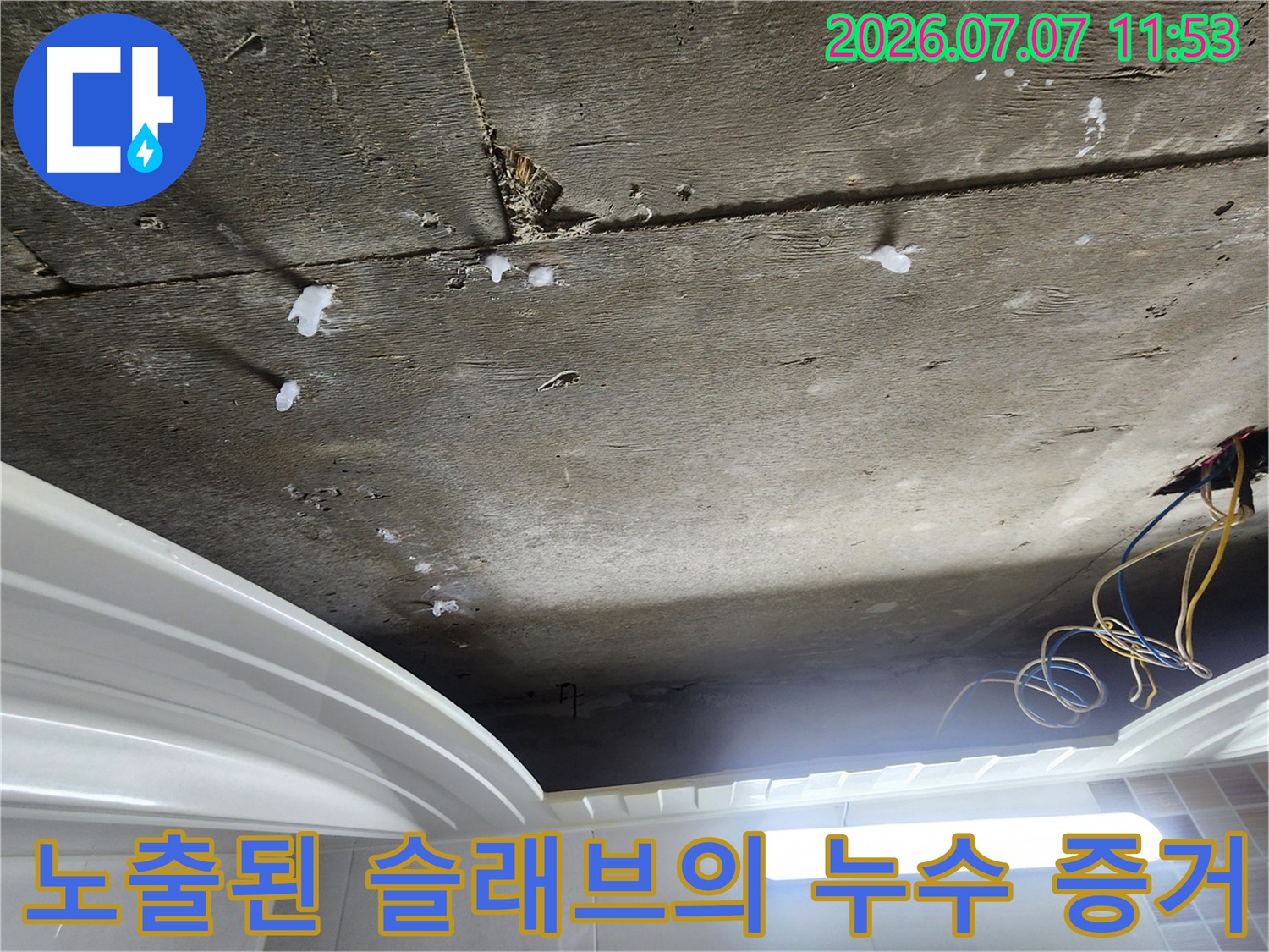 천장 상부 콘크리트 면에 형성된 누수 얼룩과 노출 배관 상태