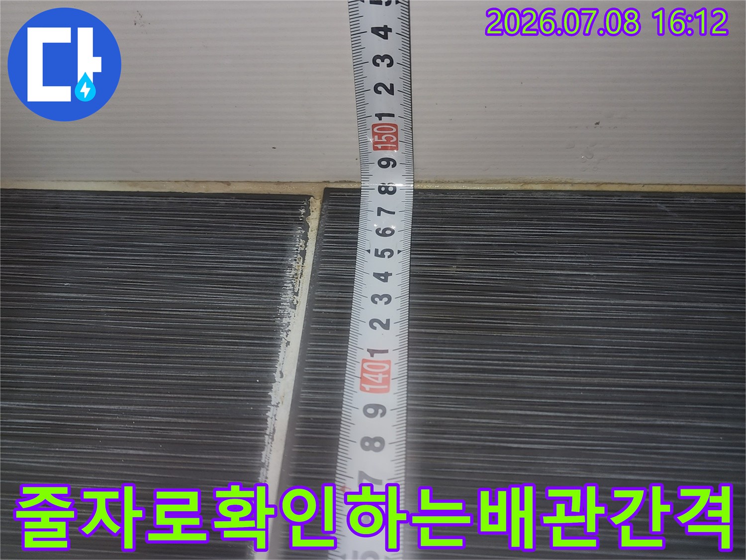 줄자를 활용하여 배관과 천장 구조물의 거리를 정확히 측정하는 장면