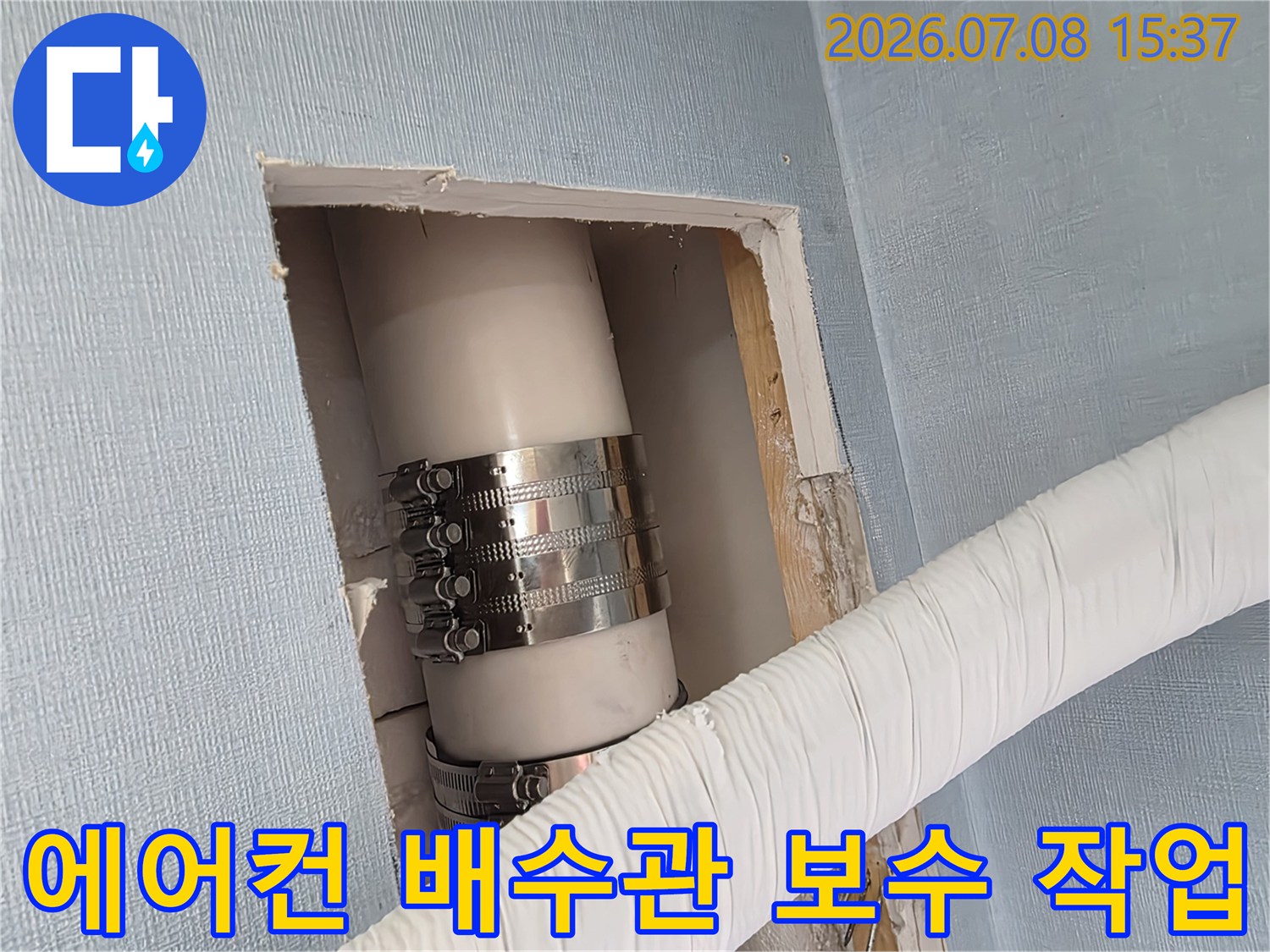 금속 밴드로 고정된 에어컨 드레인 배관과 흰색 보호재로 감싸진 주변 배관