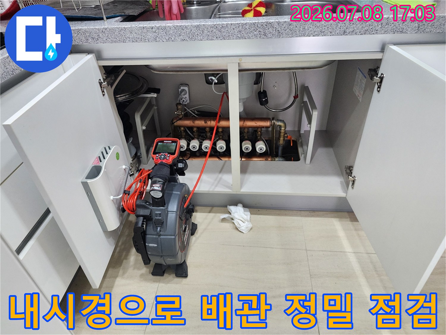 누수 위치를 파악하기 위해 내시경 장비를 활용하여 싱크대 아래 배관을 조사하는 모습