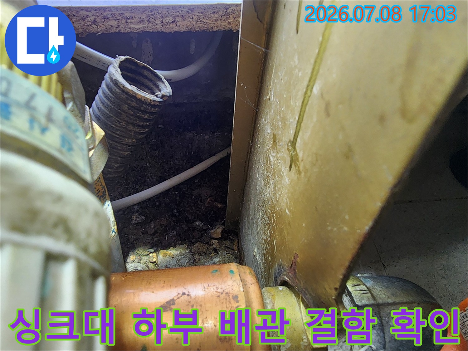 싱크대 밑 공간 내부에서 포착된 젖은 배관 부위와 주변 오염 상태