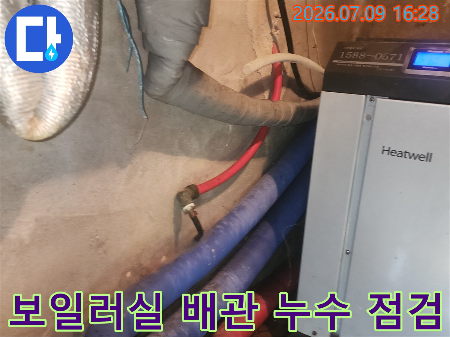 보일러실 내부의 파란색과 빨간색 배관 및 수리용 장비가 배치된 모습