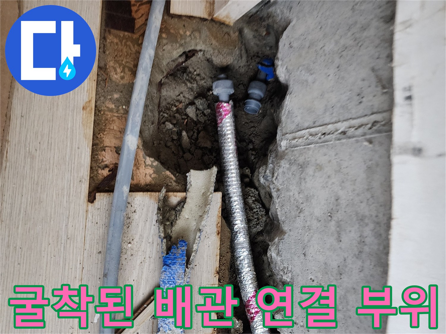 서초구 현장-바닥 시멘트 아래 노출된 은색 주름관과 파란색 관의 모습