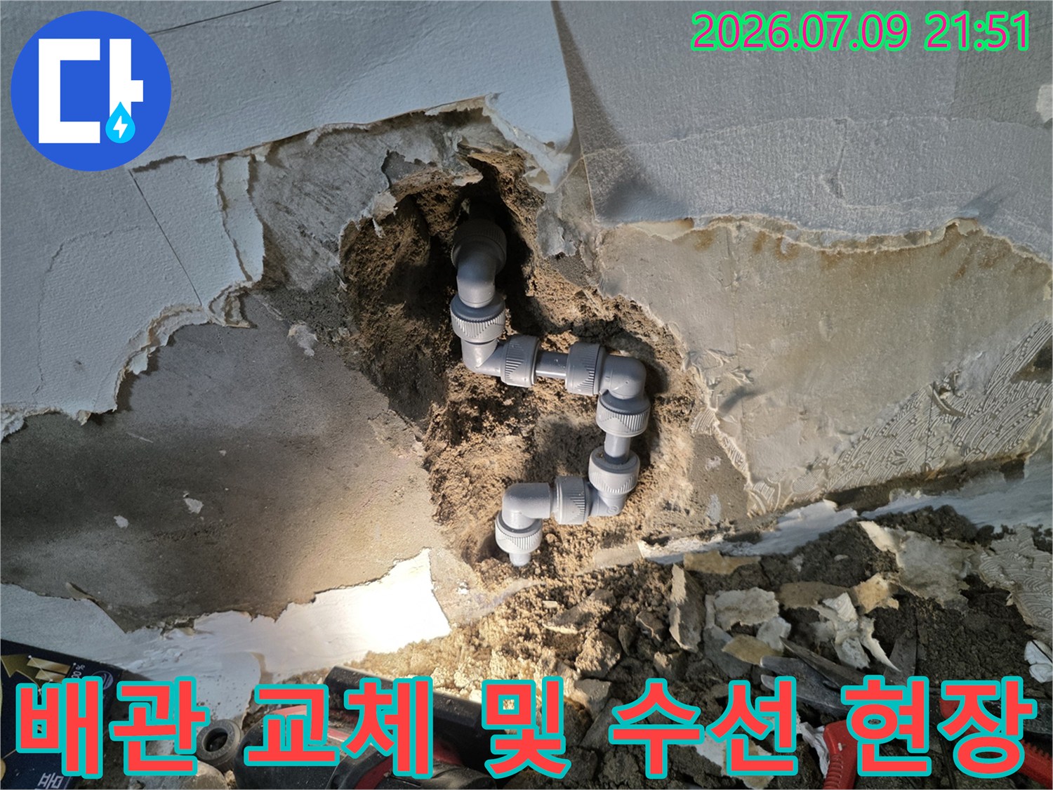 먼지투성이가 된 벽면을 뚫고 드러난 파손 배관과 작업 도구들