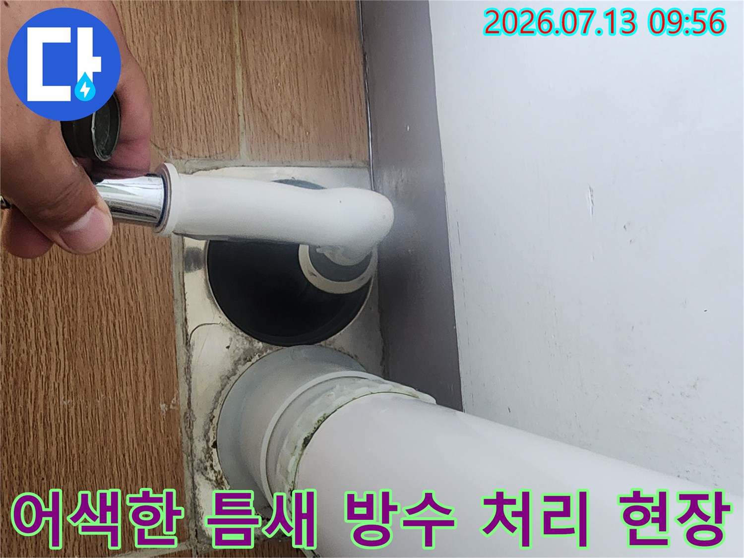 손으로 우수관 하부 연결 부위의 누수 경로를 가리키는 사진