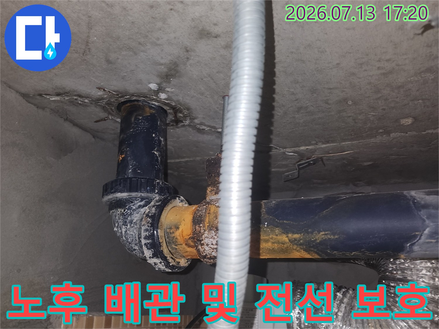 천장 안쪽의 파란색 하수관과 은색 호스로 감싸진 전기선 점검 장면
