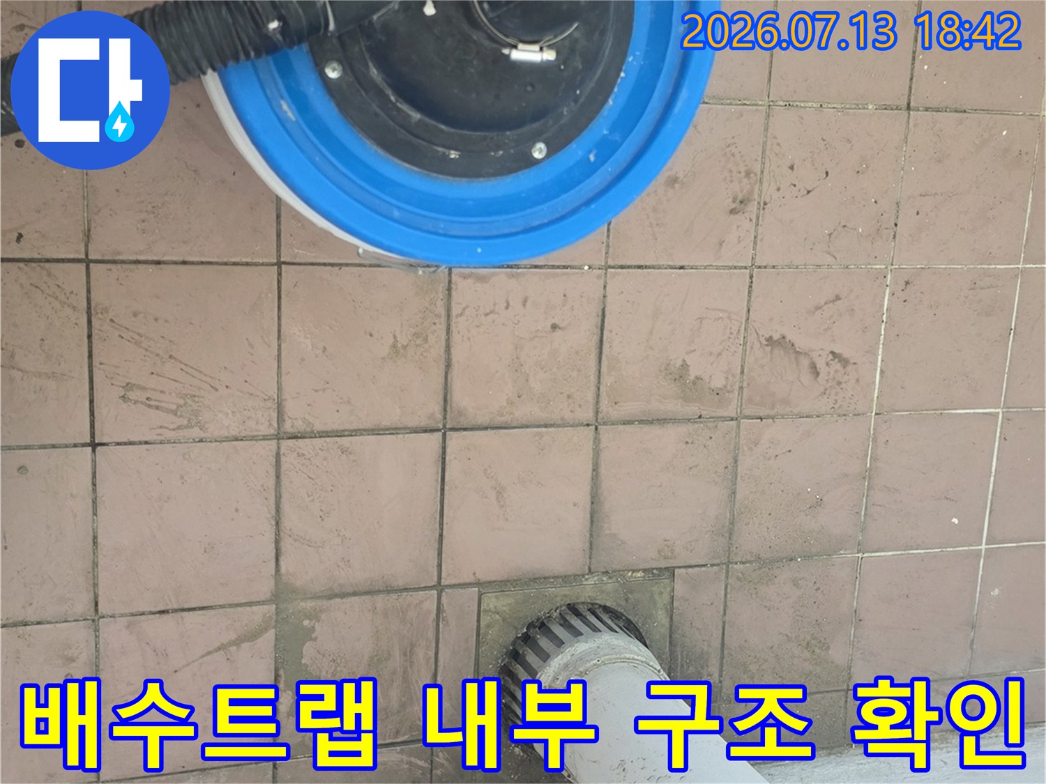 파란색 덮개와 검은색 호스가 연결된 배수구의 노후 상태 점검 장면
