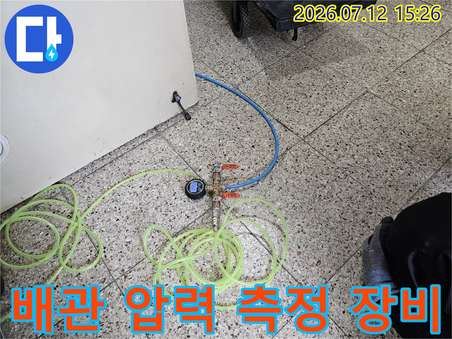 노란색 호스와 파란색 배관이 연결된 상태에서 게이지로 압력을 체크하는 현장 사진