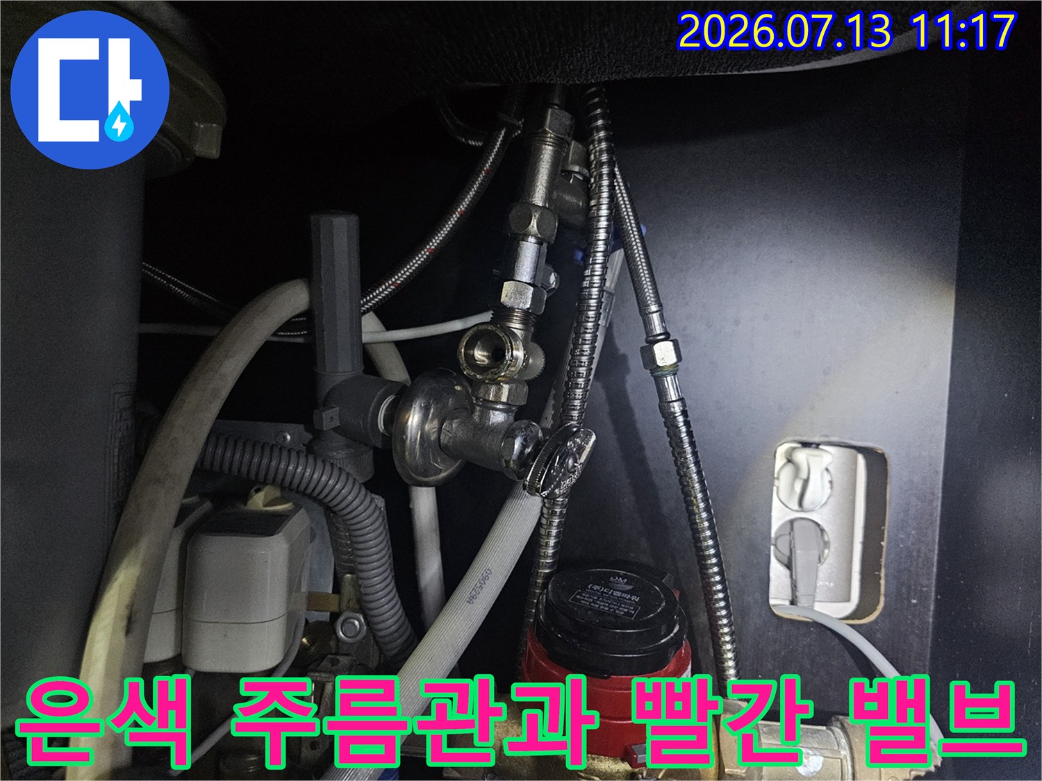 빨간색 밸브와 은색 금속제 유연 배관이 연결된 보일러 하단부-사진