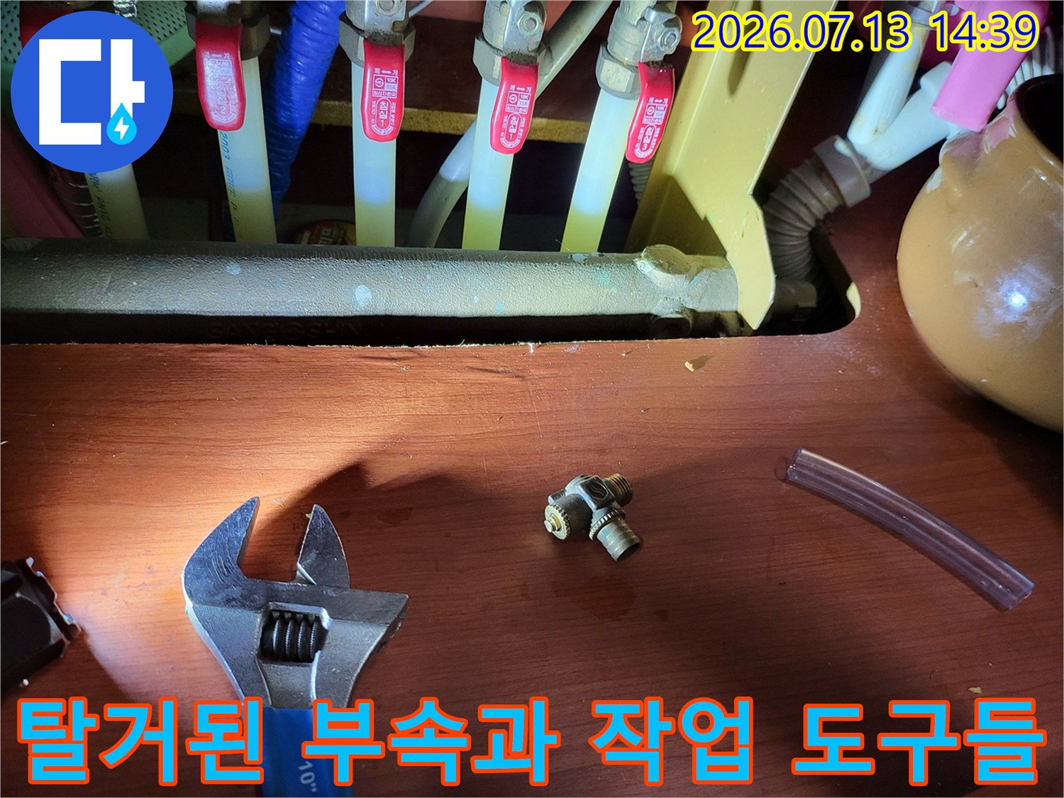 누수가 발생했던 작은 금속제 커넥터-몽키스패너와 투명 호스가 배치된 모습