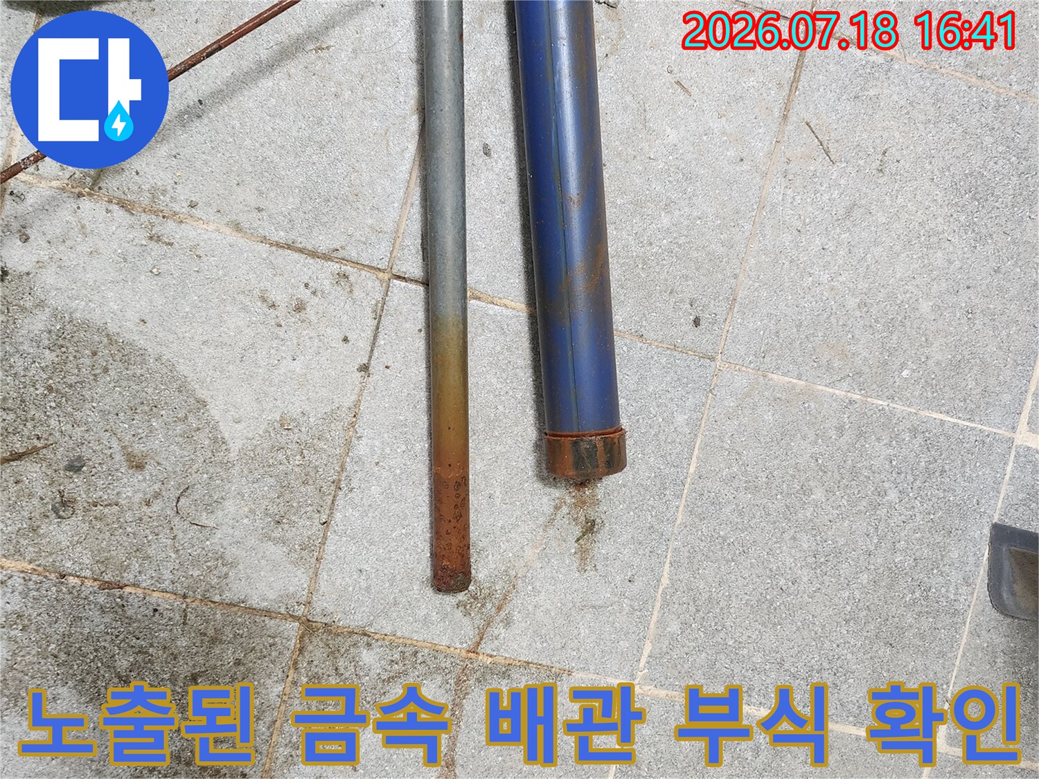 부식된 노란색금속배관과 파란색배관이 나란히 놓여있는 모습