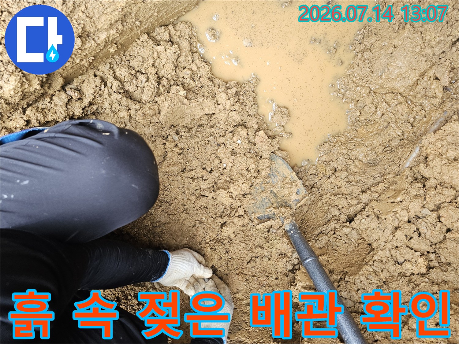 젖은 토사와 물이 고인 지점에서 작업자가 배관 누수 부위를 확인하는 모습