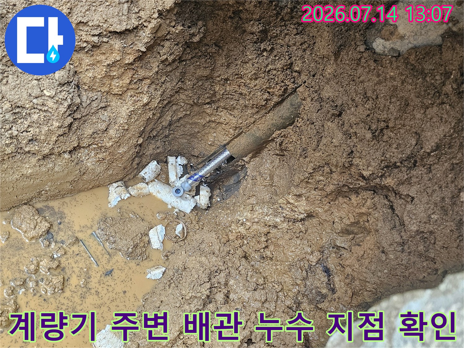흙 속에 파묻힌 노출된 수도 배관과 물이 고여 있는 현장 모습