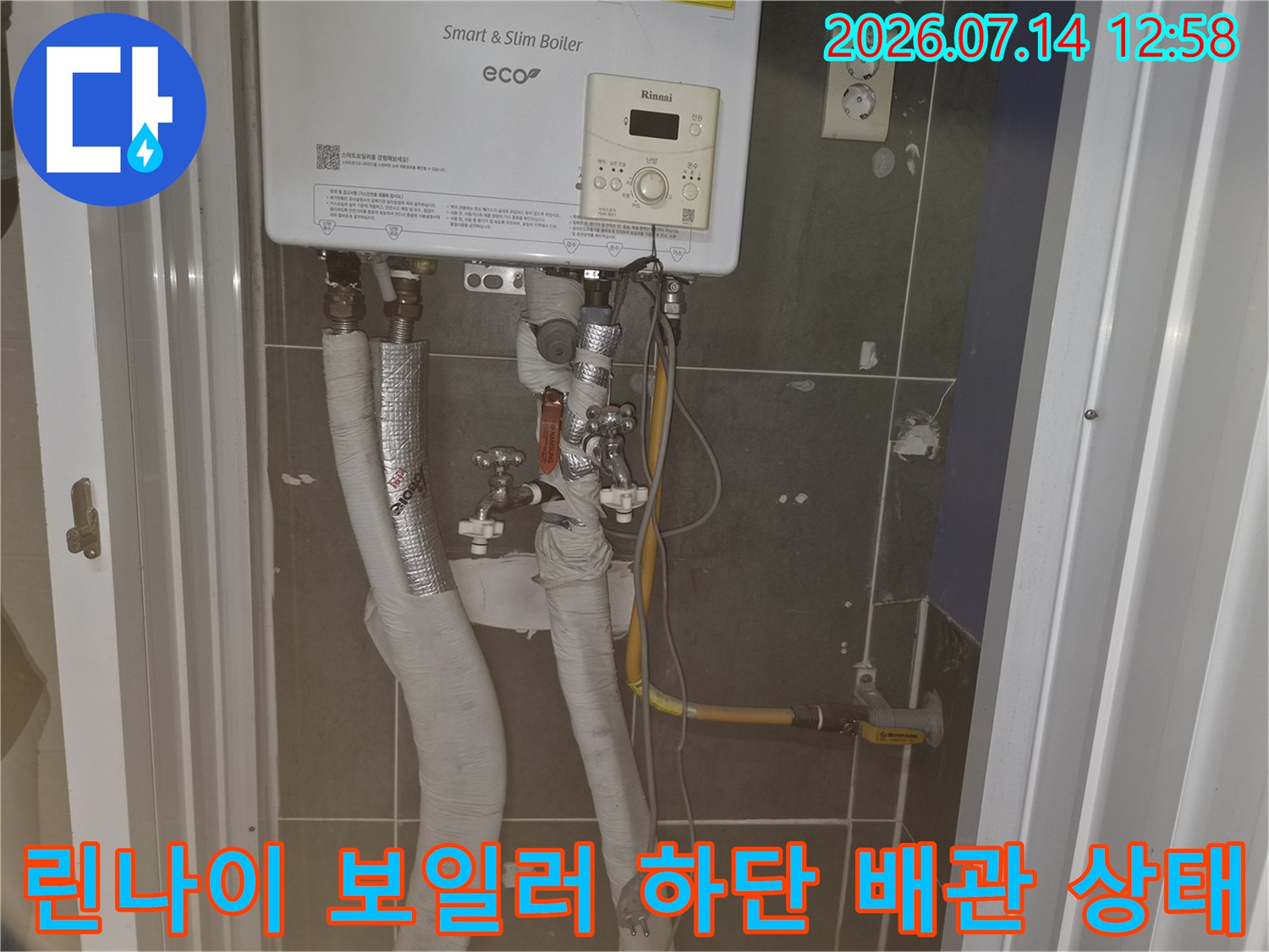 벽면에 설치된 린나이 스마트 슬림 보일러와 그 아래 연결된 은색 보온재 배관들
