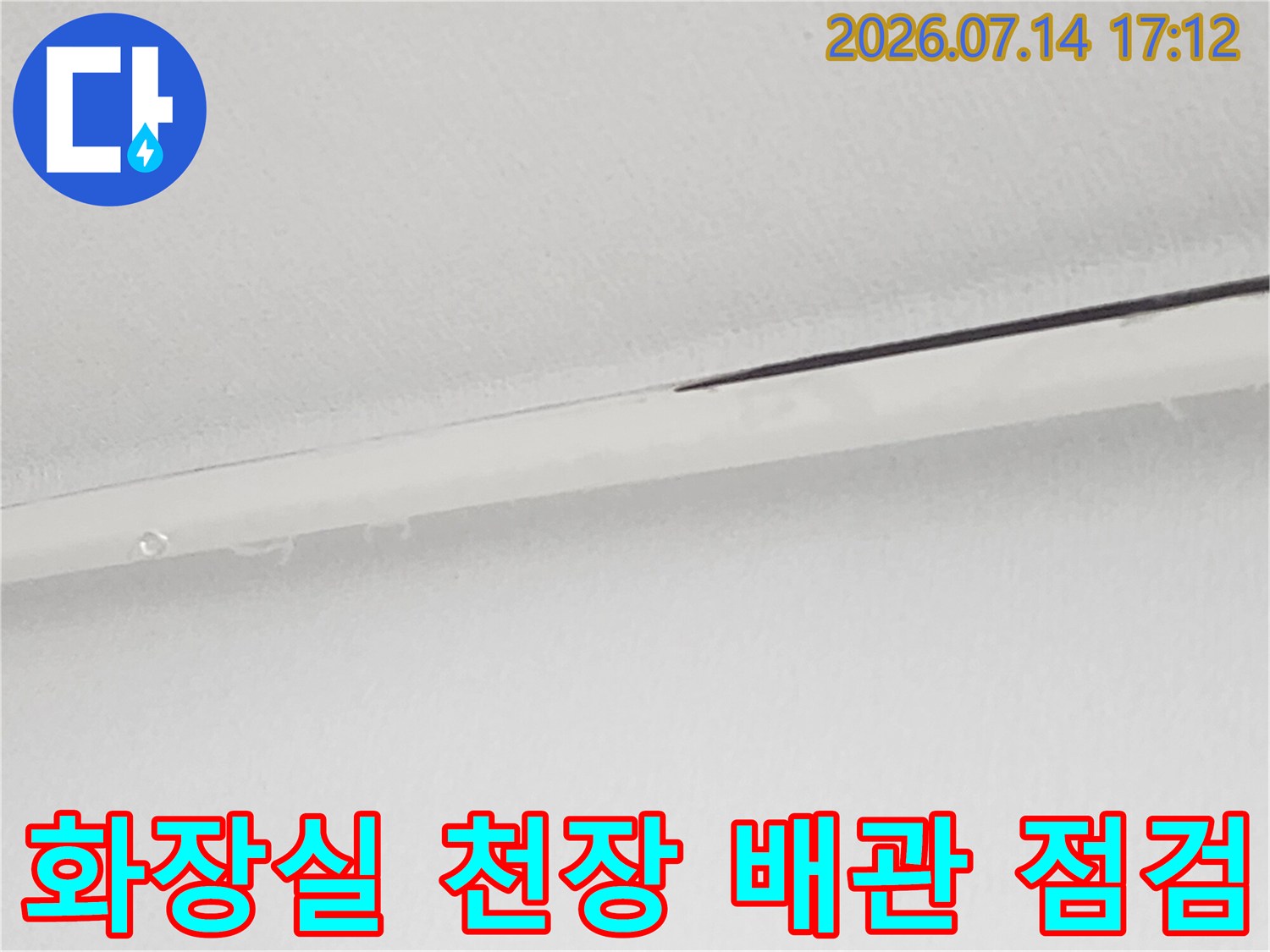 화장실 천장 내부에 노출된 하얀색 배관과 연결 부위를 점검하는 모습