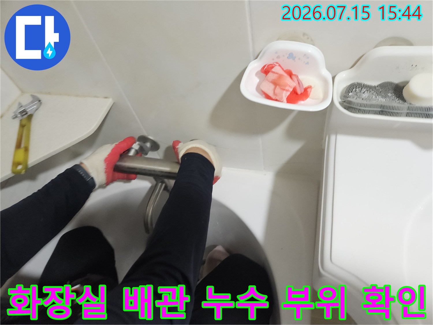 세면대 아래쪽 노출된 배관 연결부의 상태를 점검하는 장면