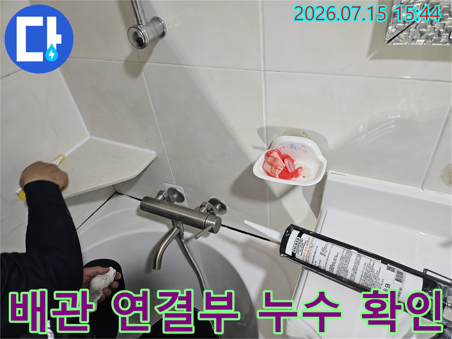 세면대 아래쪽의 복잡한 배관 구조를 점검하며 누수 부위를 파악하는 모습
