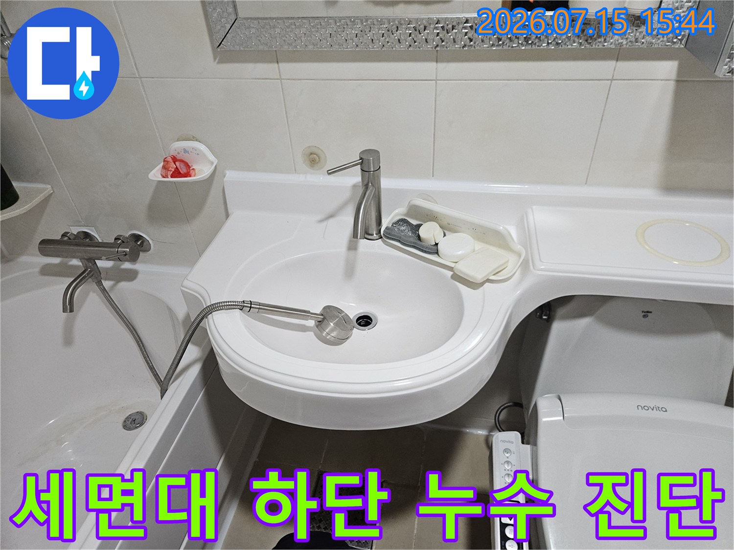 세면대 하부에 위치한 배관과 연결 부위의 상태를 정밀 점검하는 장면입니다.