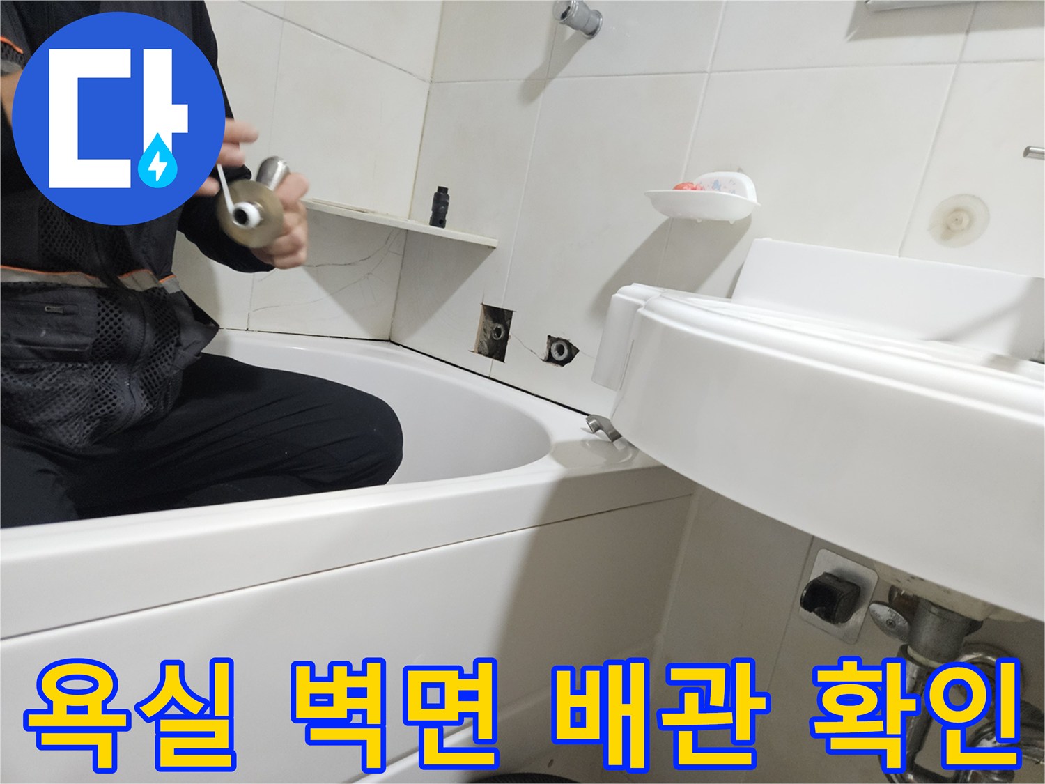 욕조 옆 타일 벽면에 노출된 배관 부속 점검 모습