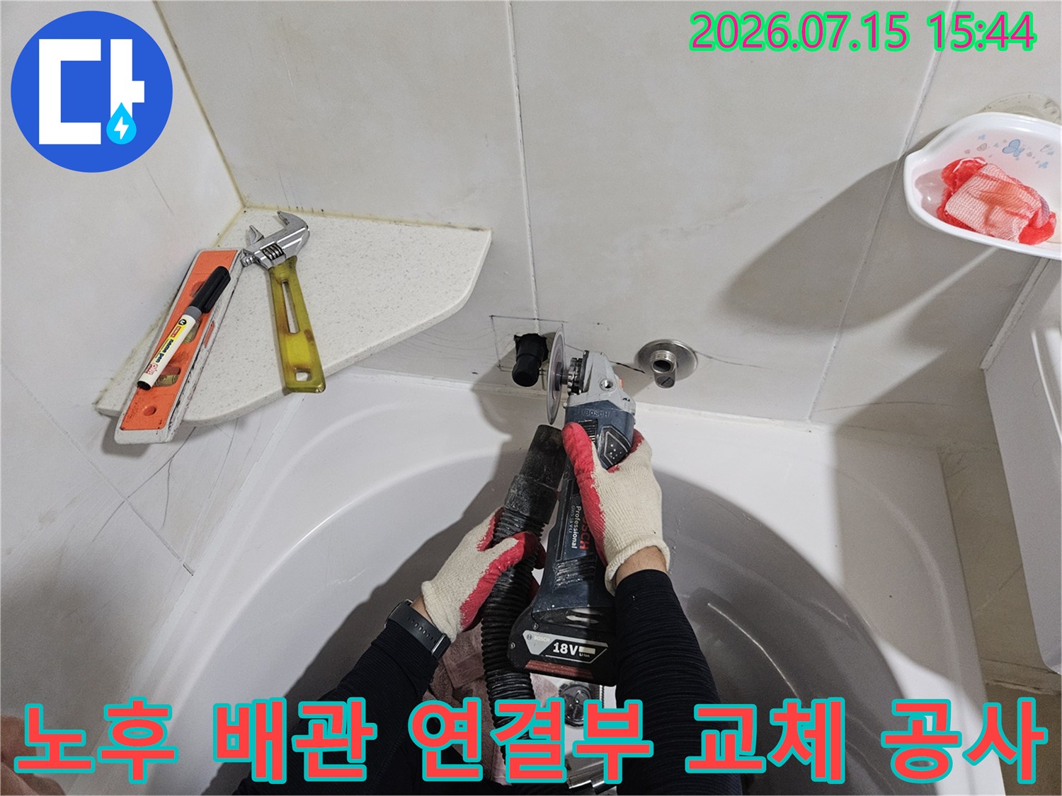 작업자가 장갑을 끼고 세면대 밑 누수 지점의 배관을 수리하는 사진