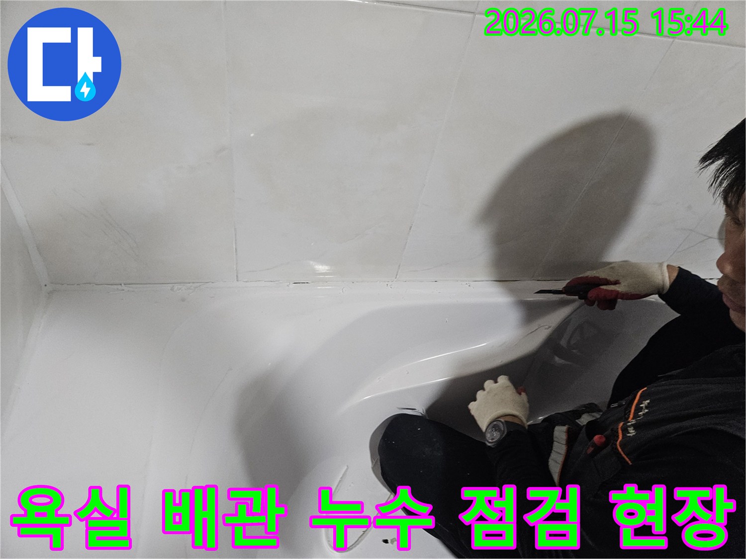 작업자가 장갑을 끼고 욕실 세면대 하단 배관 연결 부위를 확인하는 모습